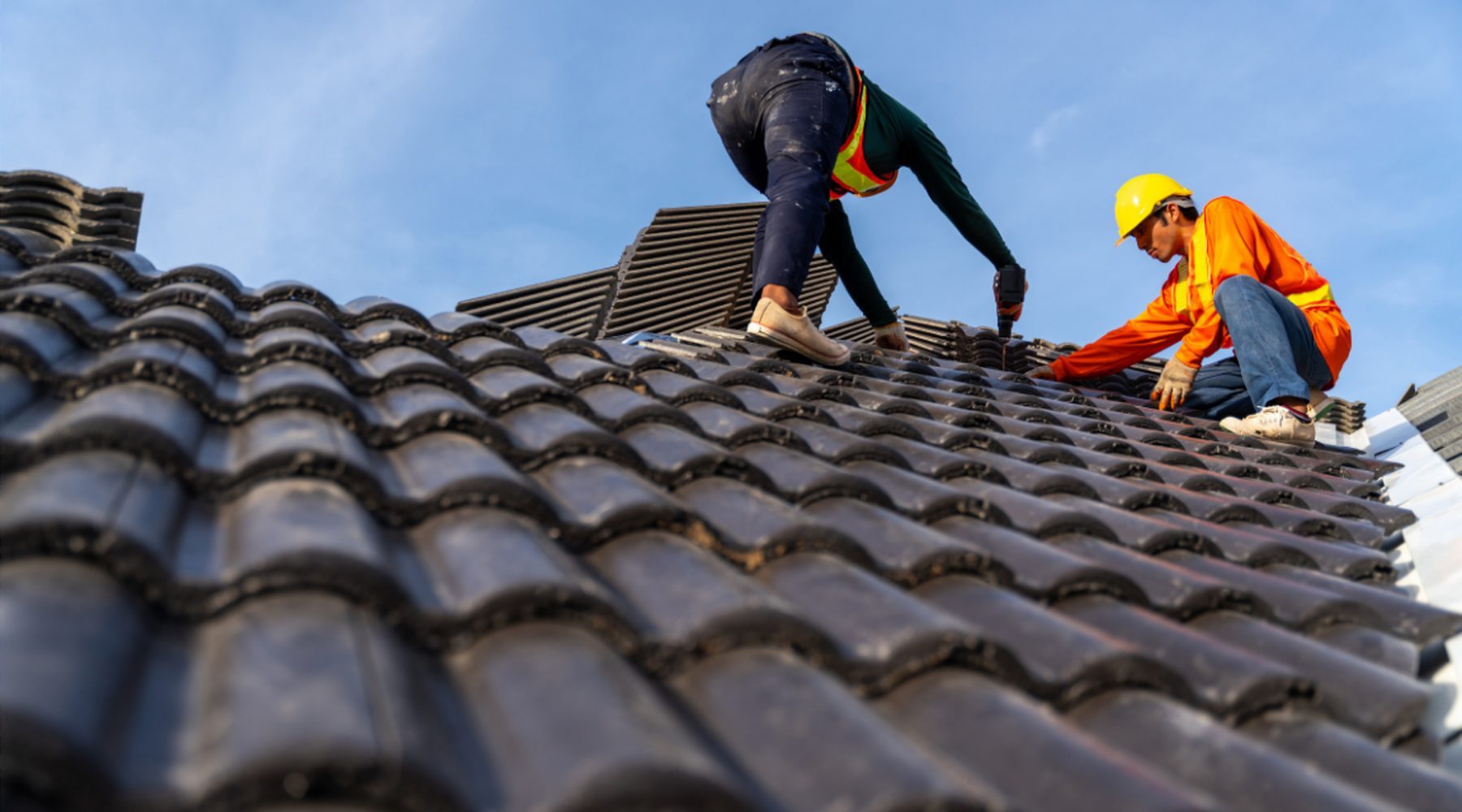 Zwei Dachdecker verlegen Dachziegel auf einem Neubau
