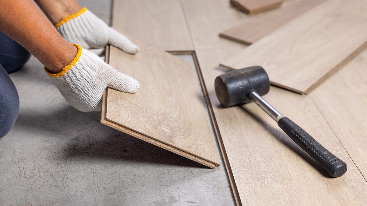 Handwerker verlegt Laminatdielen mit Gummihammer