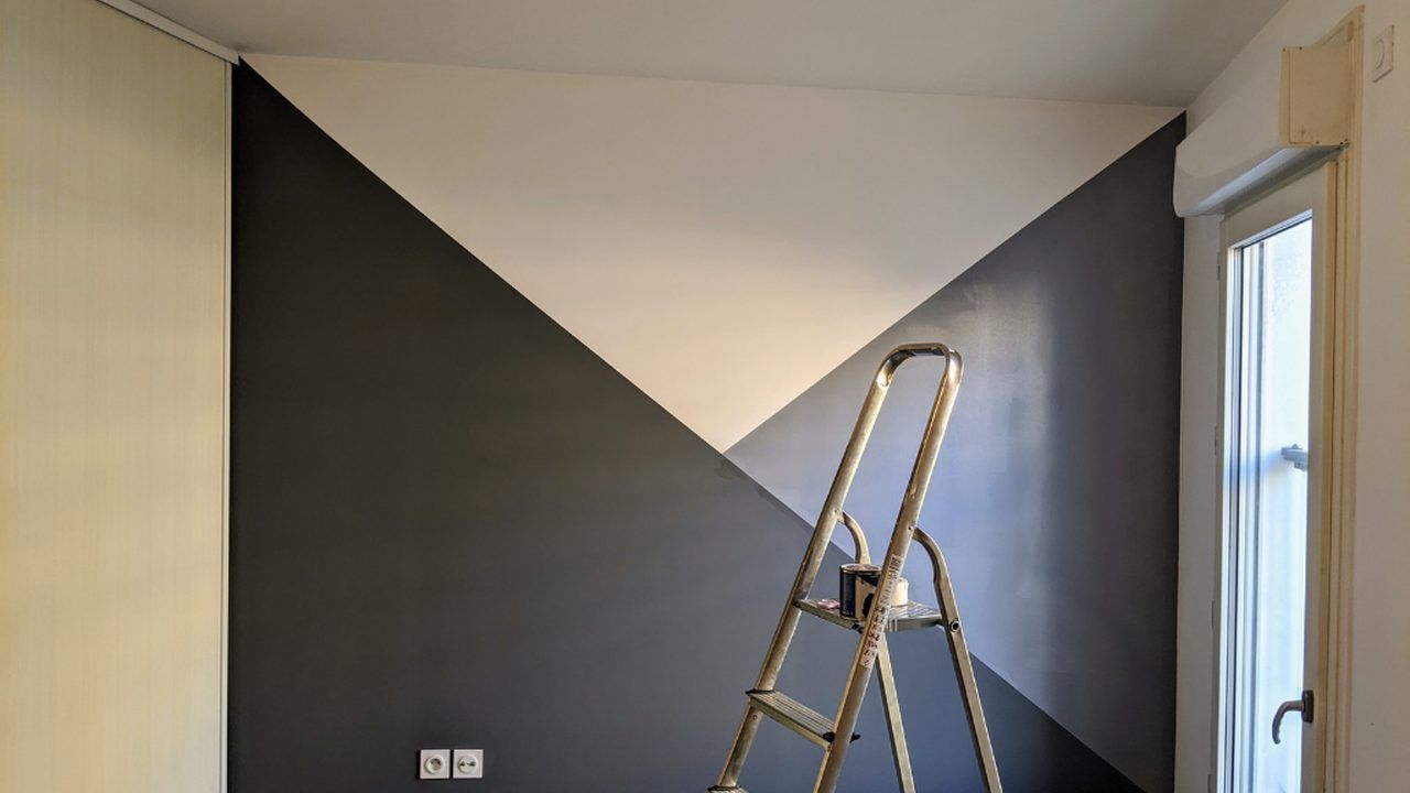 Zweifarbig gestrichene Wand mit Trittleiter und Farbrolle