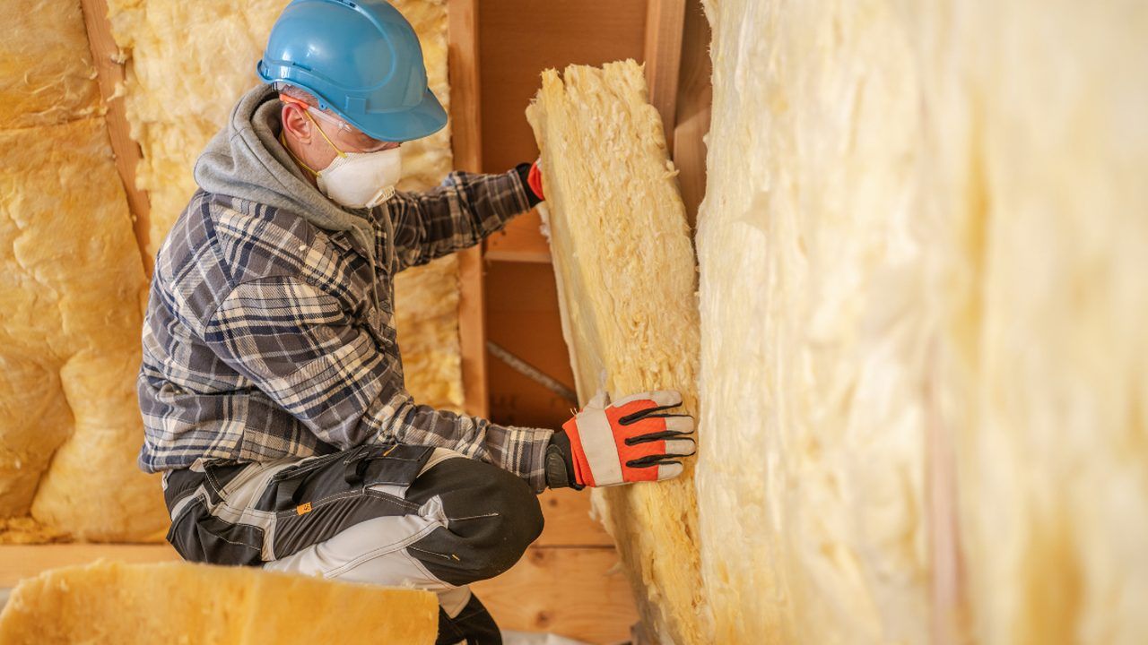Handwerker bringt Dämmwolle zwischen Holzständern an