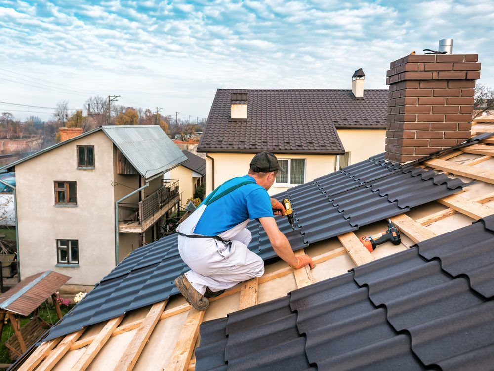 Dachdecker deckt ein Wohnhausdach mit dunklen Ziegeln neu ein